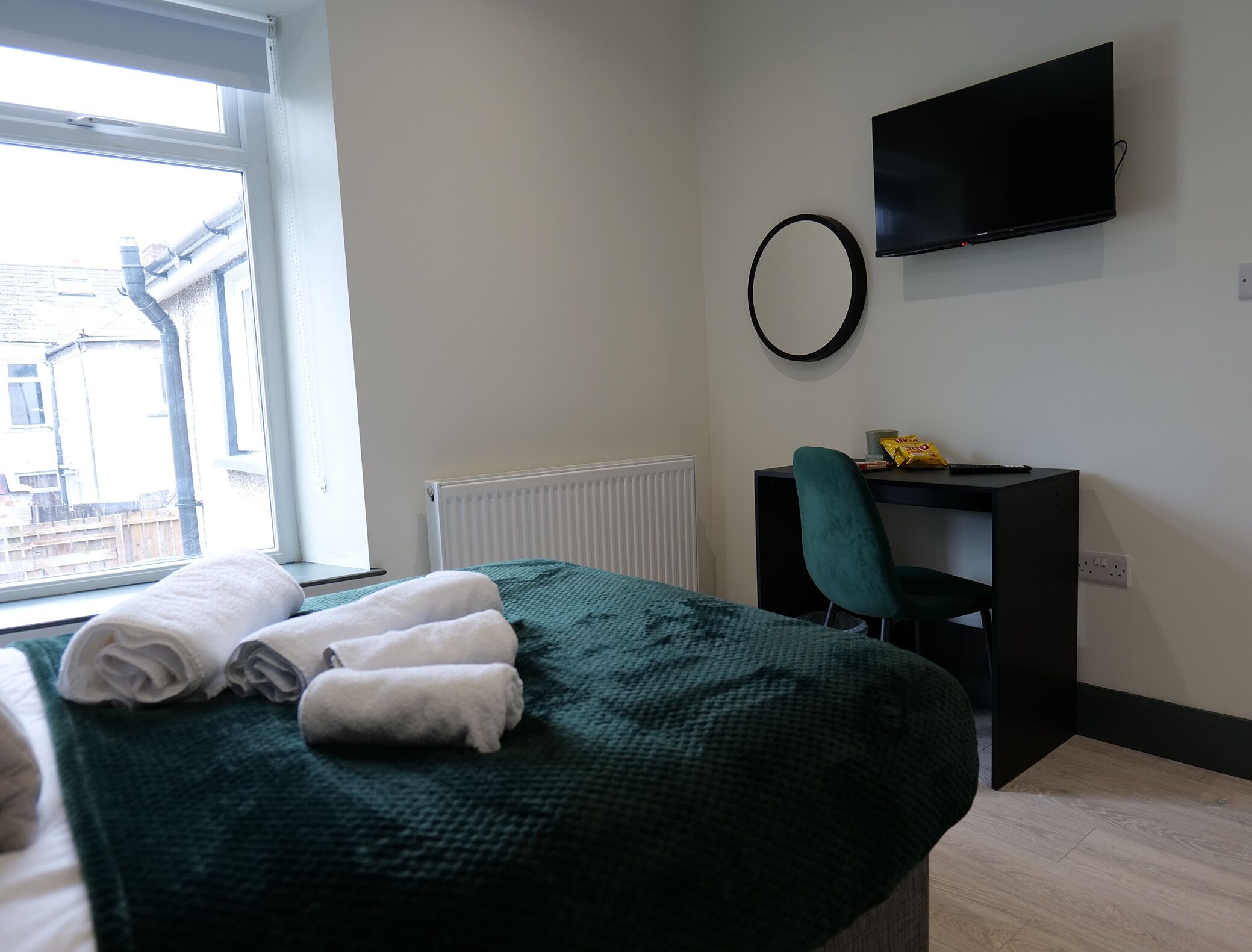 Ein Hotelzimmer mit einem Bett, einem Schreibtisch, einem Sessel, einem Fernseher und einem Fenster.