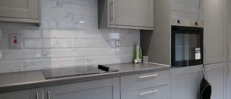 Una cocina moderna con armarios grises, una salpicadura de mármol y un horno empotrado.