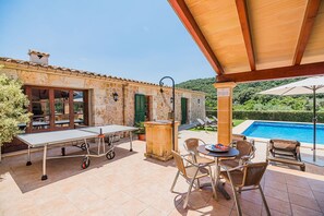 Eine Terrasse mit Pingpongtisch, Sitzgelegenheiten im Freien und einem Swimmingpool.