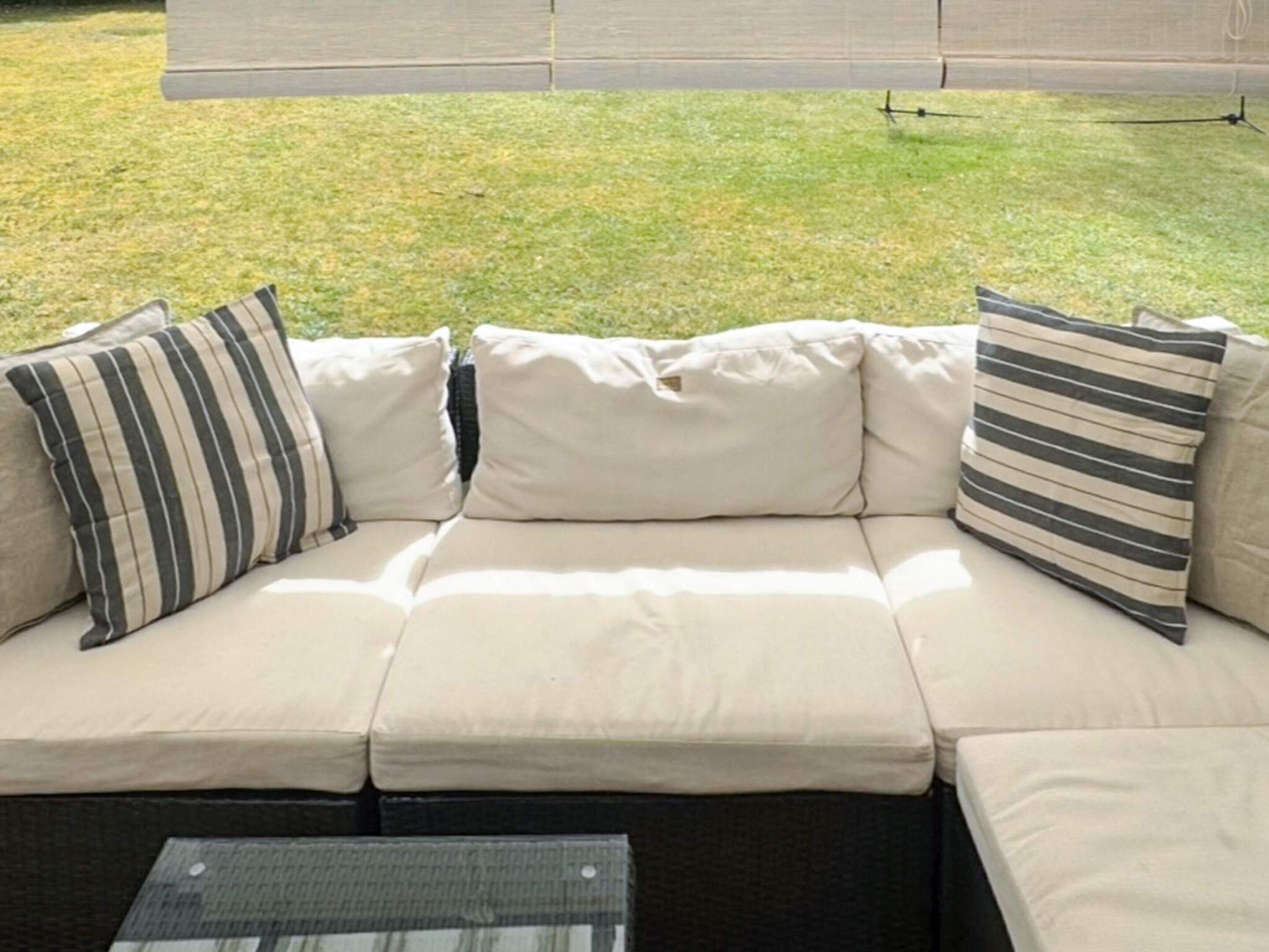 Een modulaire bank met gestreepte kussens en een glazen salontafel, buiten.