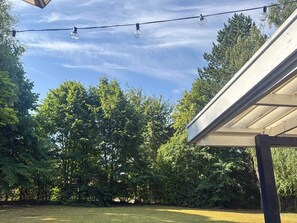 A backyard with a string of lights, a grassy lawn, and a wooden pergola. - 4 Star Holiday Home in Vig (Vig)