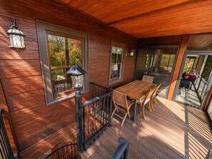 Eine Holzterrasse mit Tisch und Stühlen, großen Fenstern und einer Geländer.