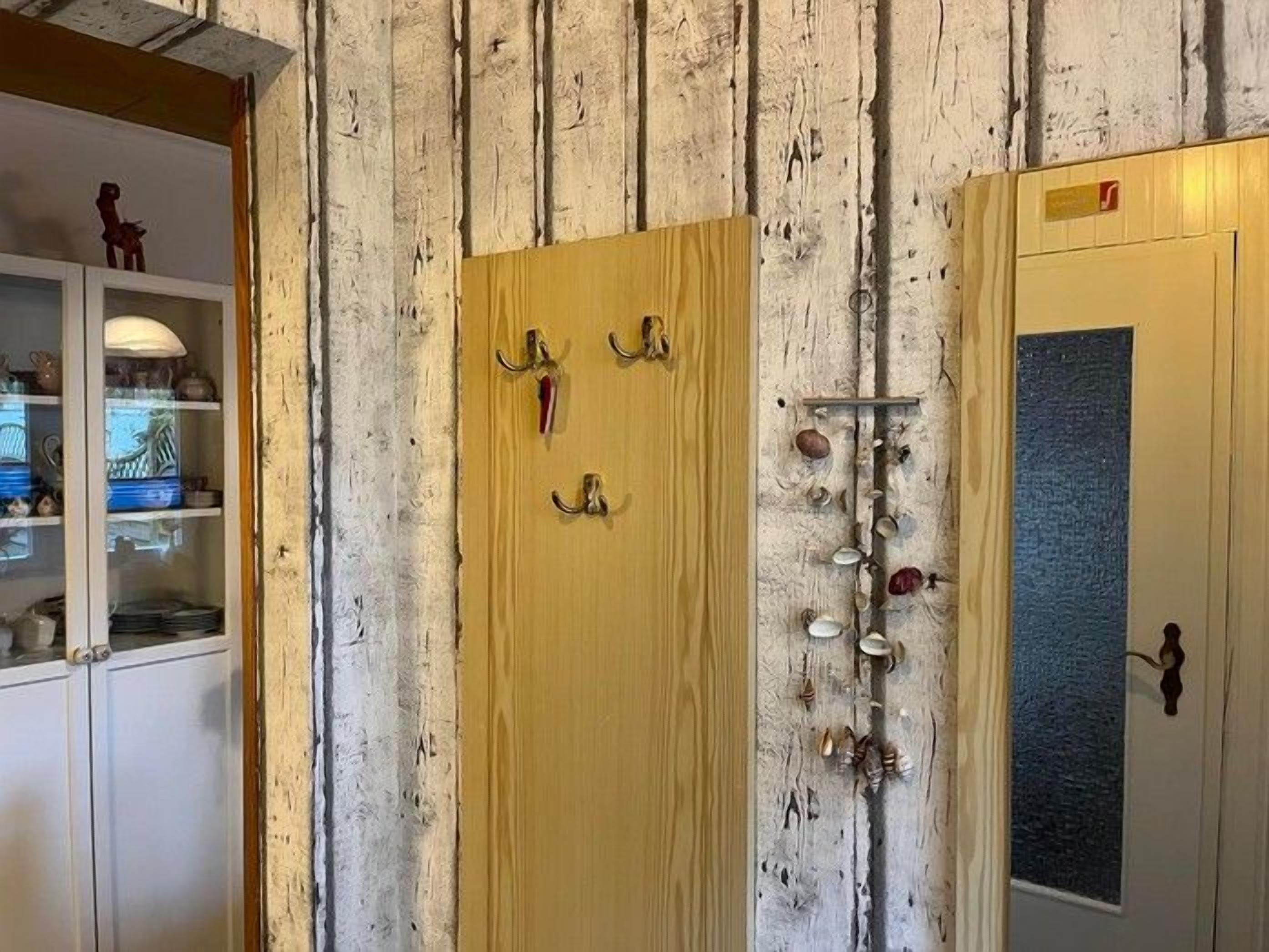 Eine Holztür mit Kleiderhaken und einem kleinen roten Gegenstand daran.