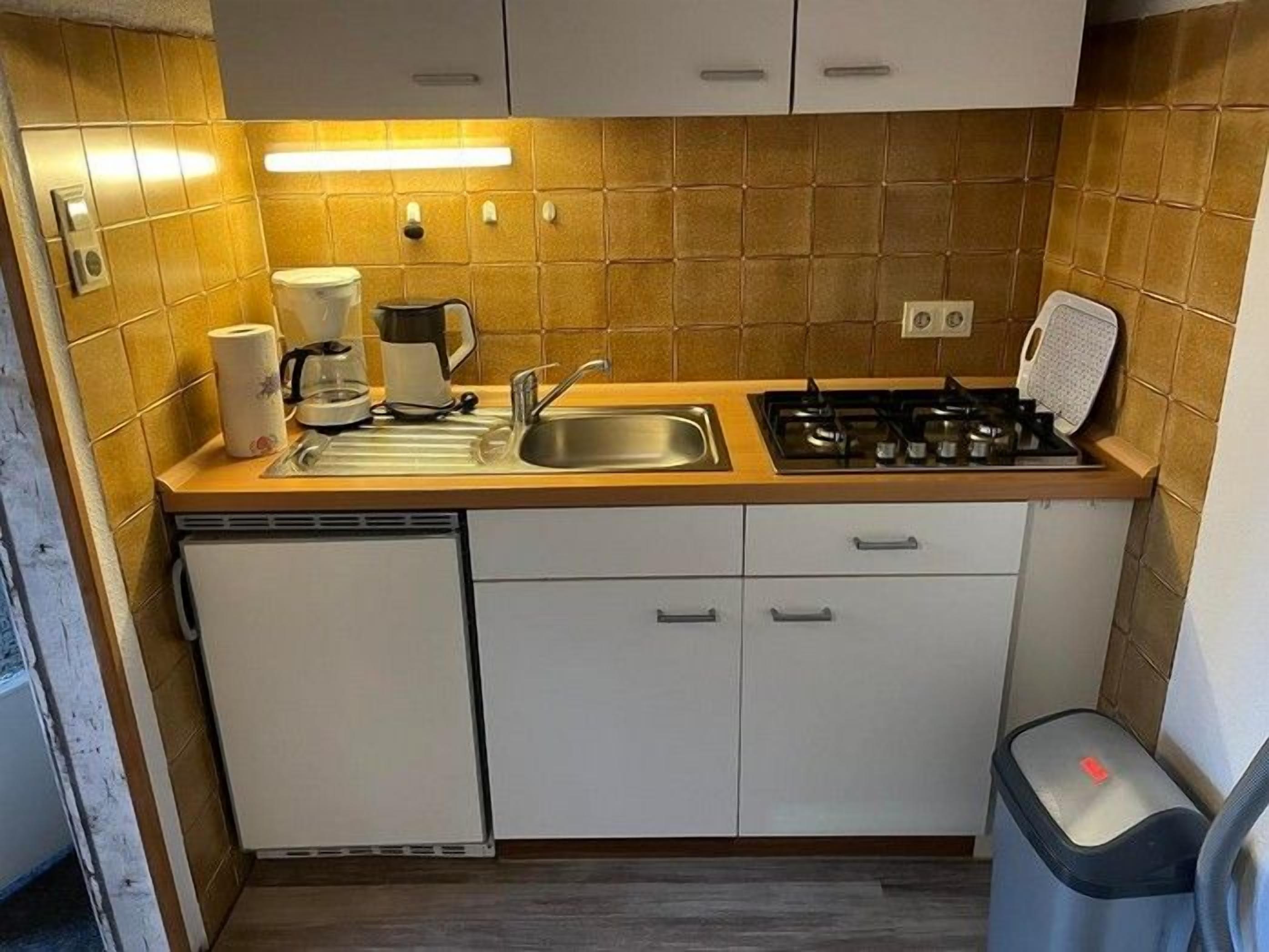 A compact kitchen with a sink, stove, and storage cabinets.