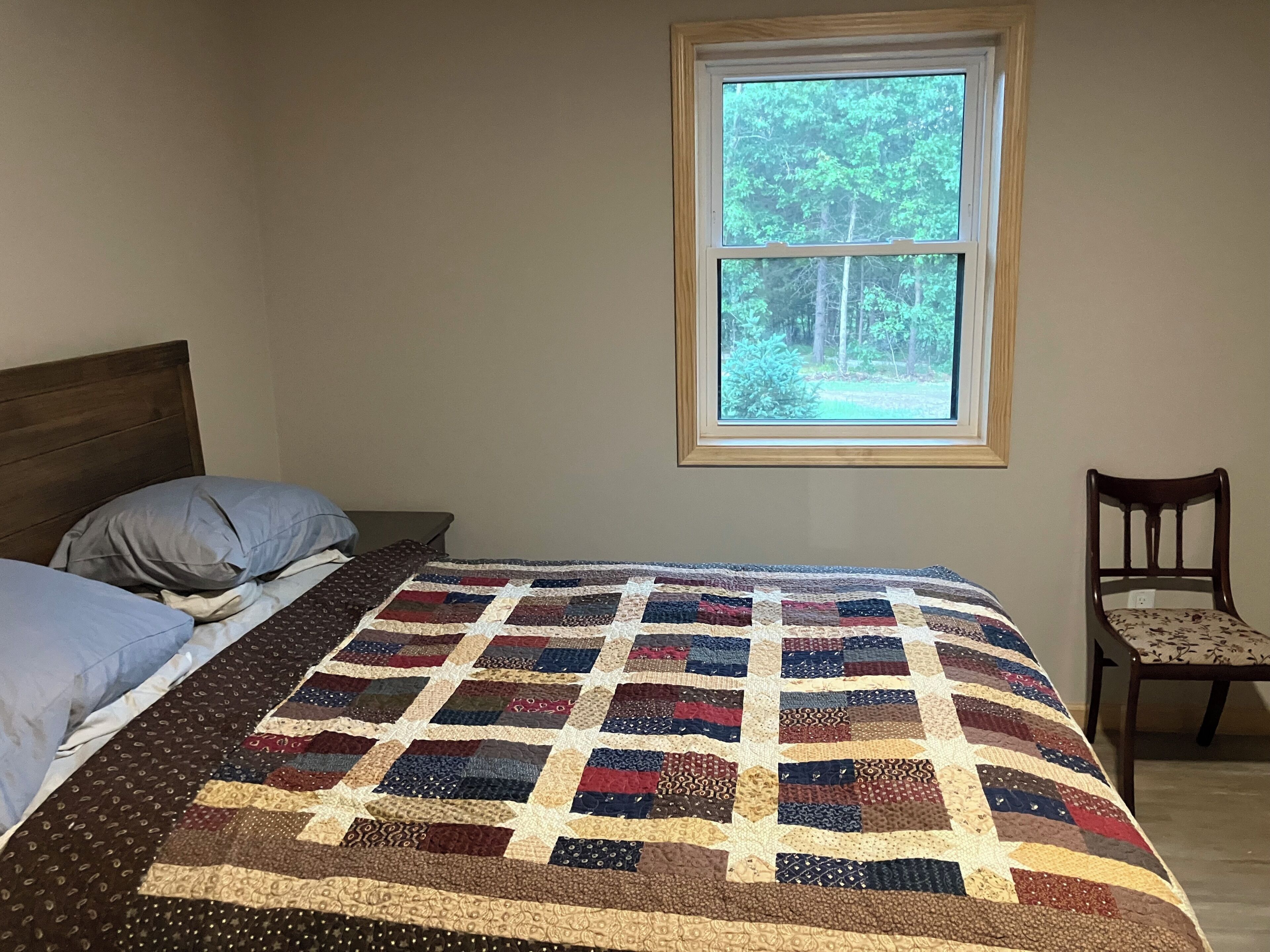 Quarto com cama, janela e cadeira.