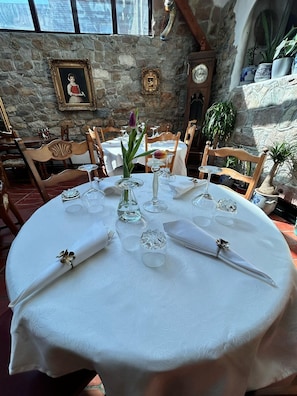 A dining table set for four with white tablecloths, glassware, and a vase with flowers. - Hotel Goldener Taler (Loerrach)