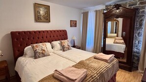 A double bed with a tufted headboard, two bedside tables, a mirror, and a painting on the wall. - Hotel Goldener Taler (Lörrach)