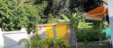 Un espace jardin agrémenté d’un chemin de gravier, d’un petit abri de jardin et d’une clôture blanche.
