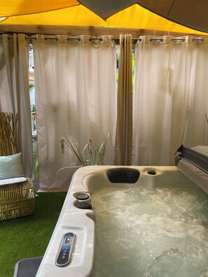 A hot tub under a yellow canopy with a control panel, surrounded by curtains and a wicker chair. - Mon petit coin de paradis - Spa privatif & calme tropical (Morne-à-l'Eau)