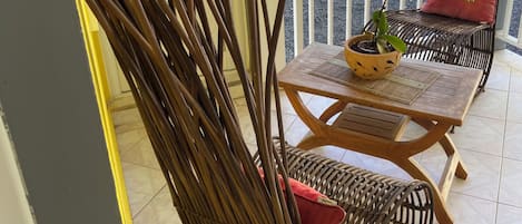 Una silla de mimbre con un cojín y una mesita con una planta en maceta.