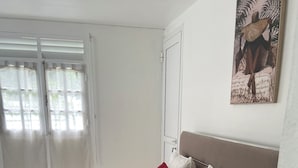 A neatly made bed with red and white pillows, a white duvet, and red towels on a white bedspread. - Mon petit coin de paradis - Spa privatif & calme tropical (Morne-à-l'Eau)