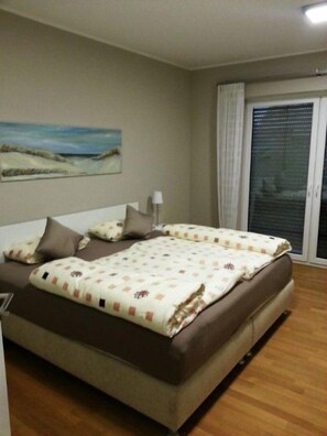A bedroom with a large bed, a nightstand, and a window with curtains. - Discover the Scheukelanders Oasis! (Borkum)