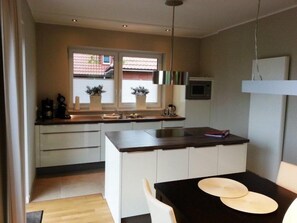 A compact kitchen with a dining area, featuring a window, built-in appliances, and a small table with chairs. - Discover the Scheukelanders Oasis! (Borkum)