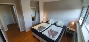 Een slaapkamer met een bed, nachtkastjes, een spiegel en een raam.