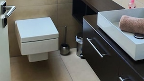 Ein kleines Badezimmer mit Toilette, Waschbecken und Ablageschränken.
