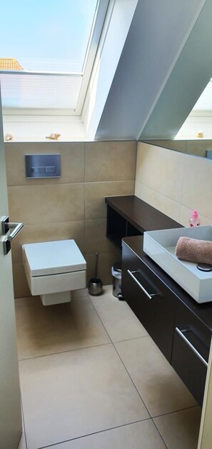 Een kleine badkamer met toilet, wastafel en opbergkasten.