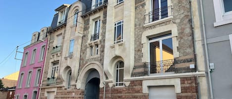 A row of multi-story buildings with stone facades, arched doorways, and balconies.