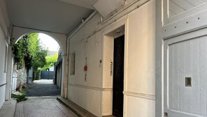A corridor with a tiled floor, a door with a number plate, and a wall-mounted fire alarm. - Nice Apartment in Cherbourg for 4 Guests (Cherbourg-en-Cotentin)