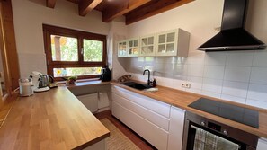 A kitchen with wooden countertops, a built-in oven, a window with a view, and white cabinets. - Koppelblick Vacation Home - My SWH (Murg)