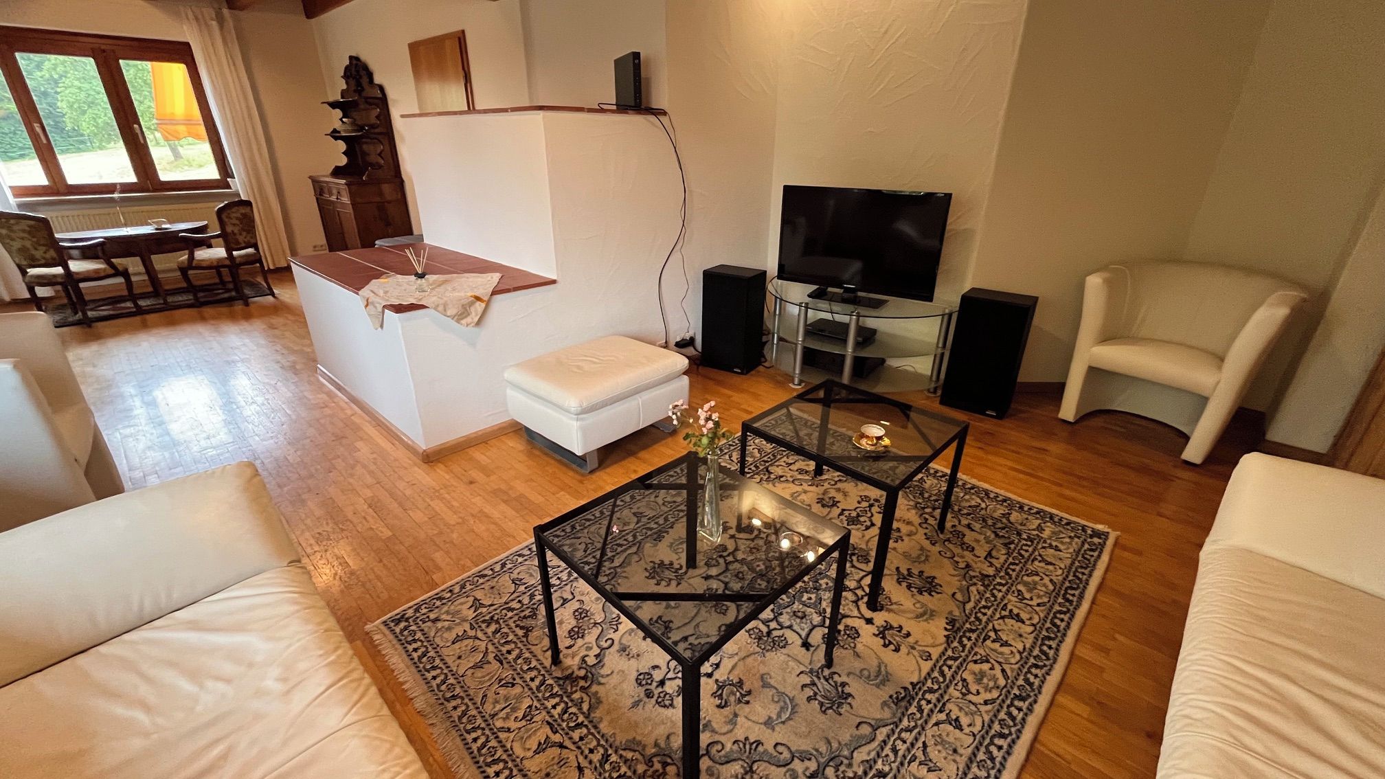En stue med sofa, sofabord, fjernsyn og spiseområde med bord og stole.