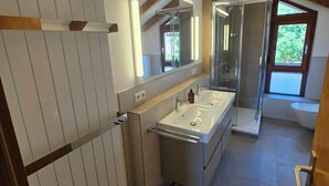 Un baño moderno con tocador de doble lavabo, un espejo grande y cabina de ducha.