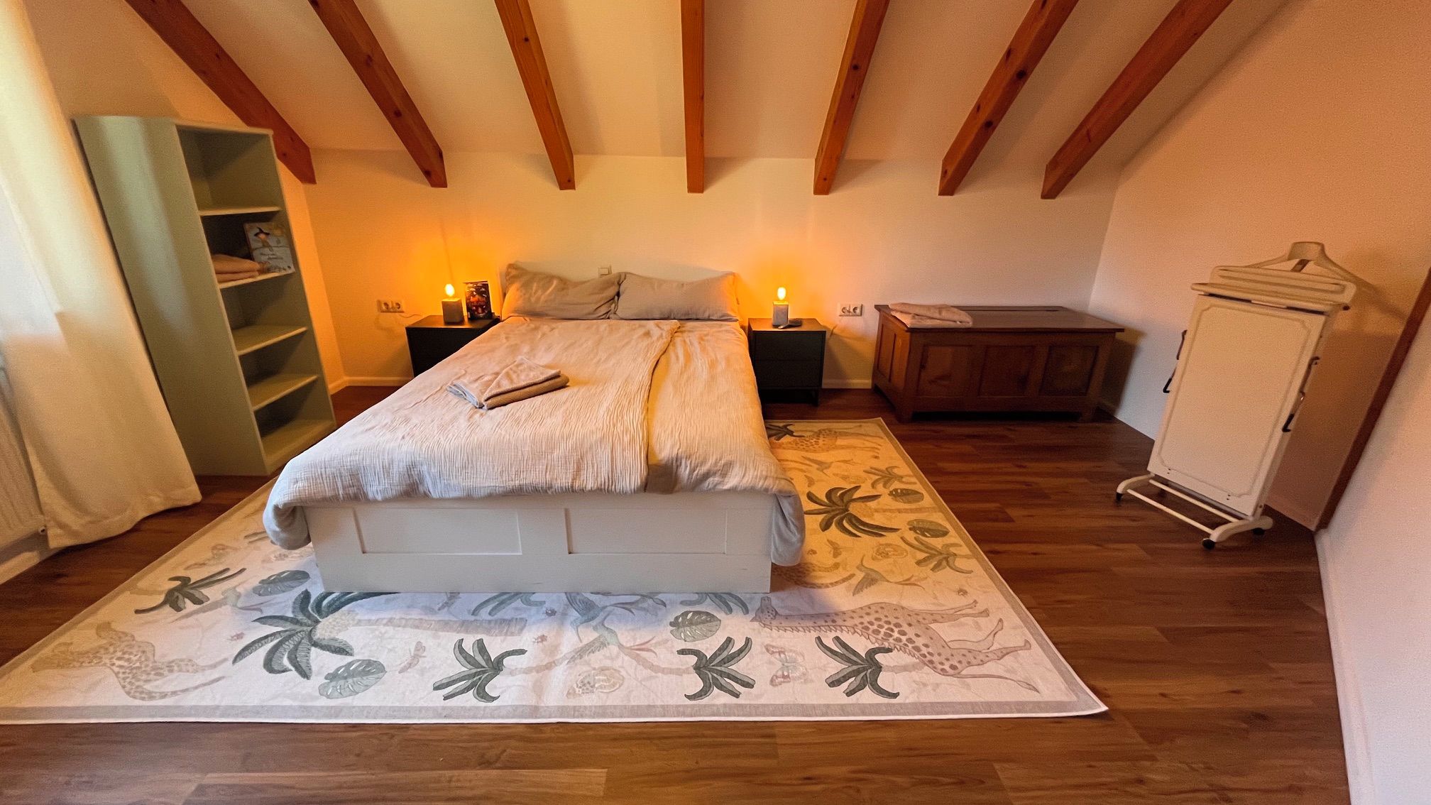 Ein Schlafzimmer mit einem Bett, Nachttischen, einem Kleiderschrank und einem gemusterten Teppich.