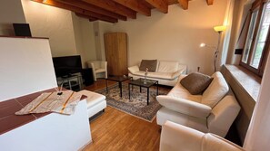 A living room with a sofa, coffee table, and a television.