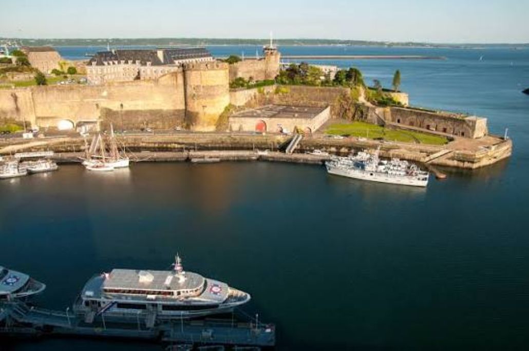 A fortified castle with a moat, surrounded by calm water.