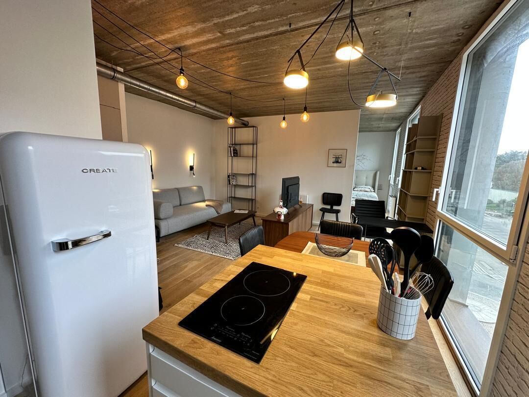 A modern kitchen with a white refrigerator, wooden countertop, and a built-in stove.