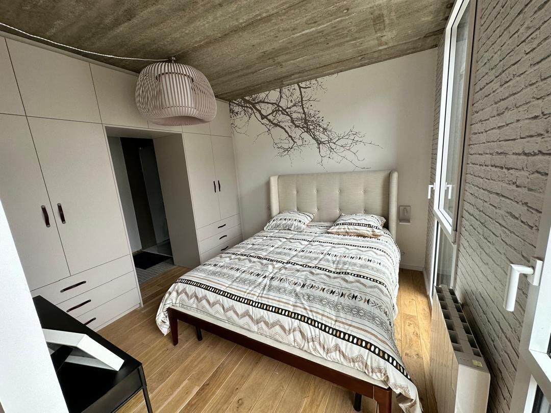 A bedroom with a bed, wardrobe, and a hanging light fixture.