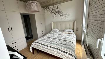 A bedroom with a bed, wardrobe, and a hanging light fixture.