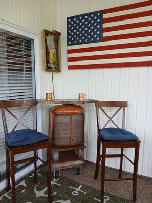Une pièce d’angle avec une table en bois, deux chaises, un radiateur et un drapeau américain.