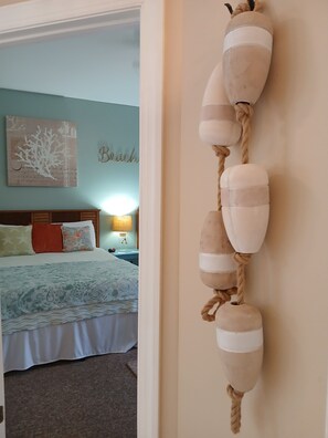 Ein Zimmer mit einem Bett, einer Wanddekoration aus Seil und einer Wand, auf der das Wort 'Beach' steht.