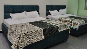 Una habitación de hotel con dos camas, un ventilador de techo y una lámpara moderna.