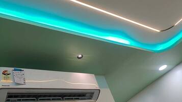 An air conditioning unit mounted on a wall with a ceiling light fixture.