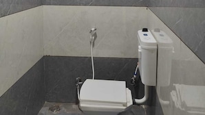 Un baño pequeño con azulejos, un inodoro, un secador de manos y un calentador de agua.