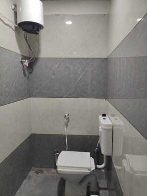 Een kleine betegelde badkamer met toilet, handdroger en boiler.