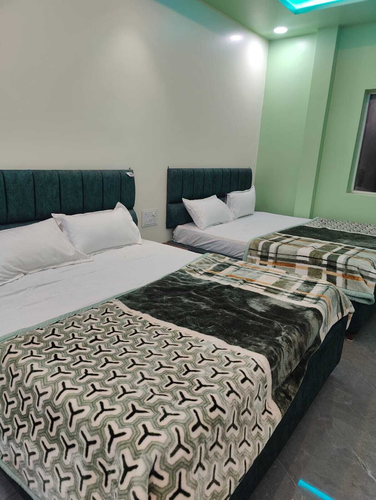 A hotel room with two beds, each with a headboard and pillows.