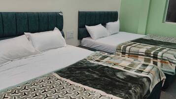 A hotel room with two beds, each with a headboard and pillows.