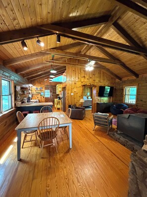 A spacious cabin interior with a dining area, seating, and a television.