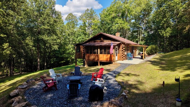 Un chalet rustique doté d’un patio, entouré d’arbres.