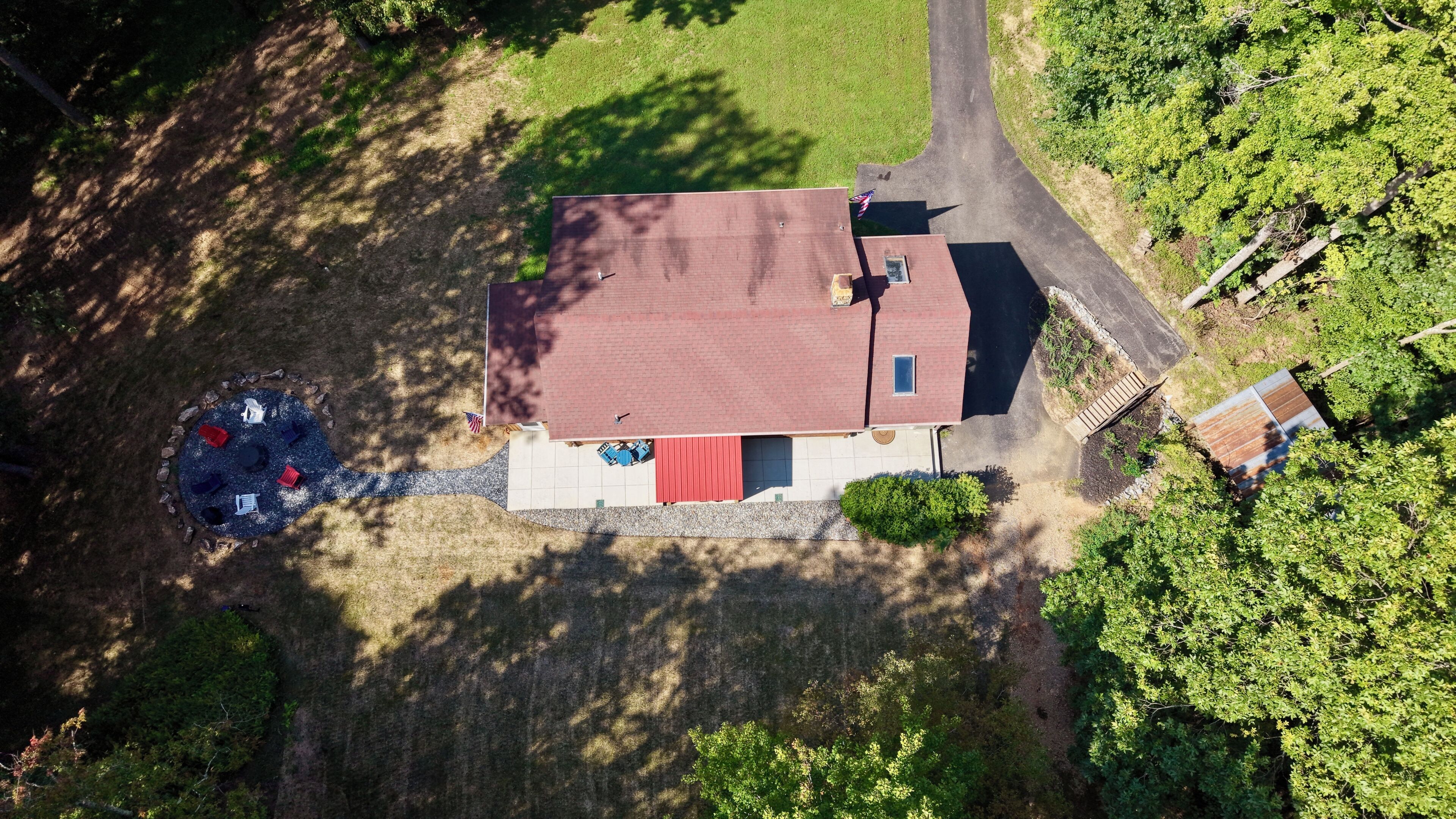 Una vista aerea di una casa con tetto rosso, vialetto e un piccolo giardino.