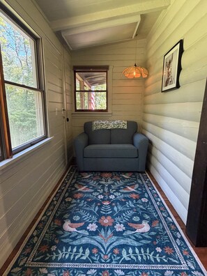 A narrow hallway with a gray sofa, a patterned rug, and a framed picture on the wall.