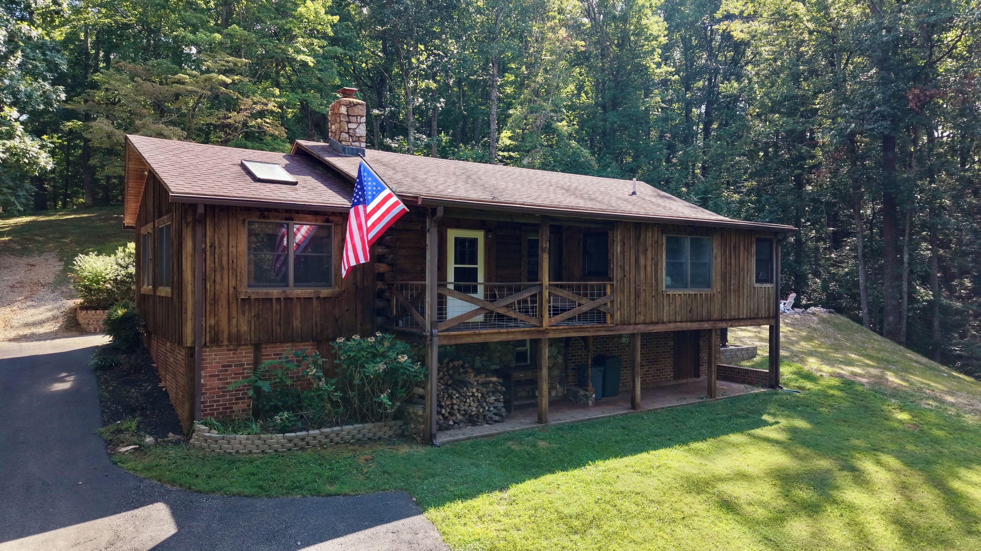 Una casetta di legno con un portico, un camino e una bandiera americana.