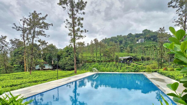 A swimming pool with a clear view of the surrounding lush greenery and terraced hills. - Estate IV By Zomestay (Vythiri)