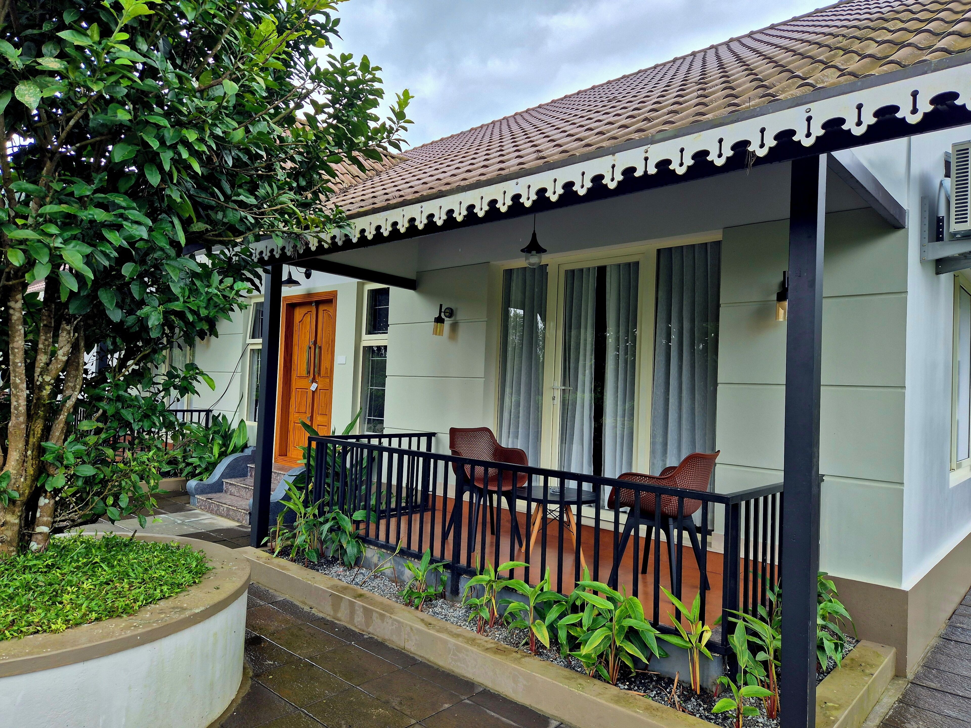 A house with a tiled roof, a porch with chairs, and a large window.