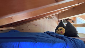Een stapelbed met een blauwe matras en een kussen met een vrolijk gezicht.
