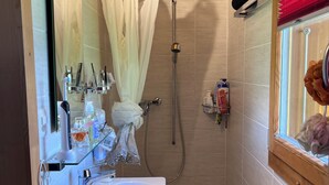 Een badkamer met een douche, een wastafel en een spiegel.