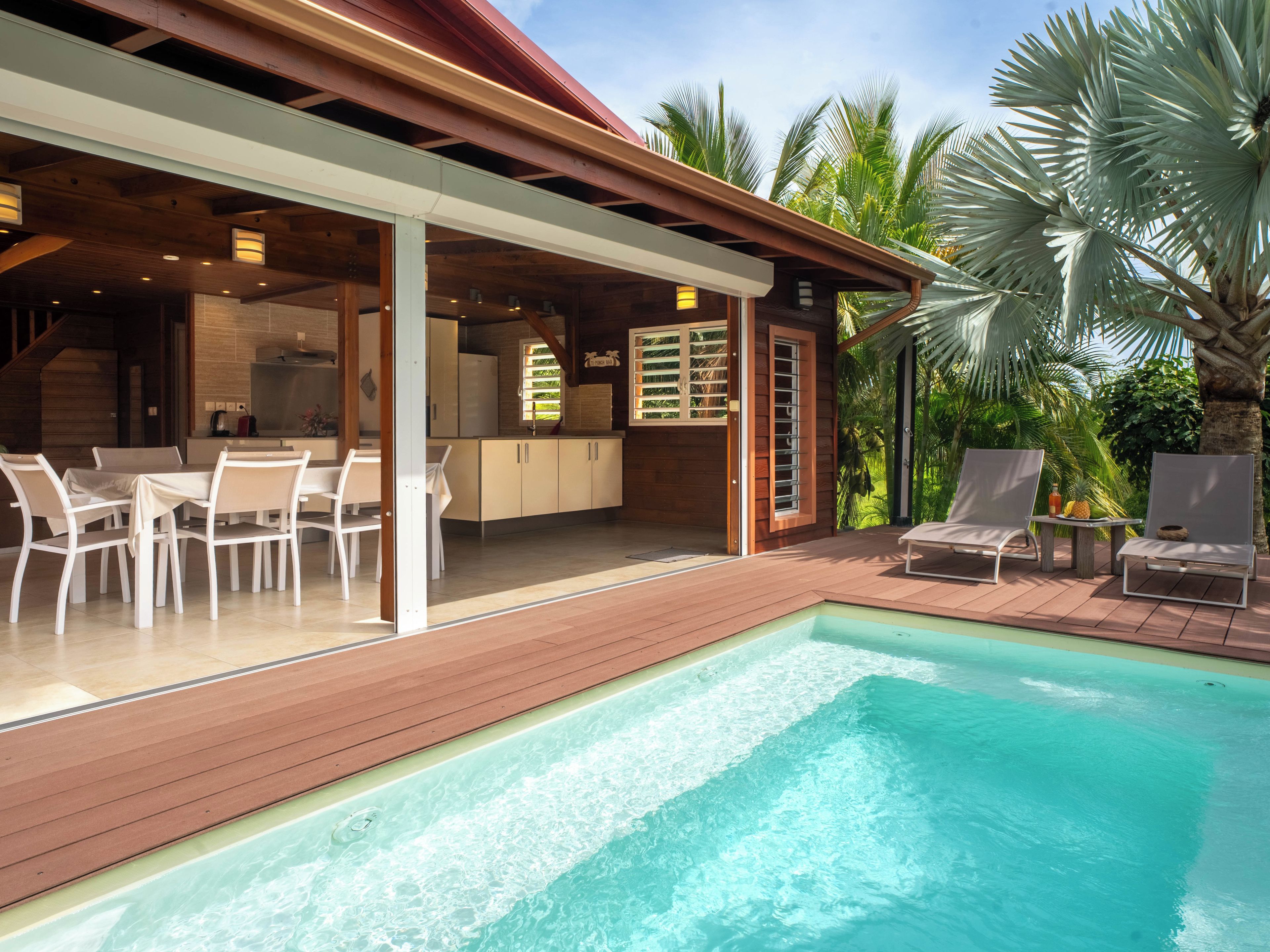 A poolside area with a dining set, lounge chairs, and a view of the pool.