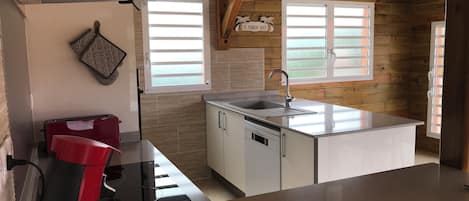 A compact kitchen with a sink, a red appliance, and a window with blinds.